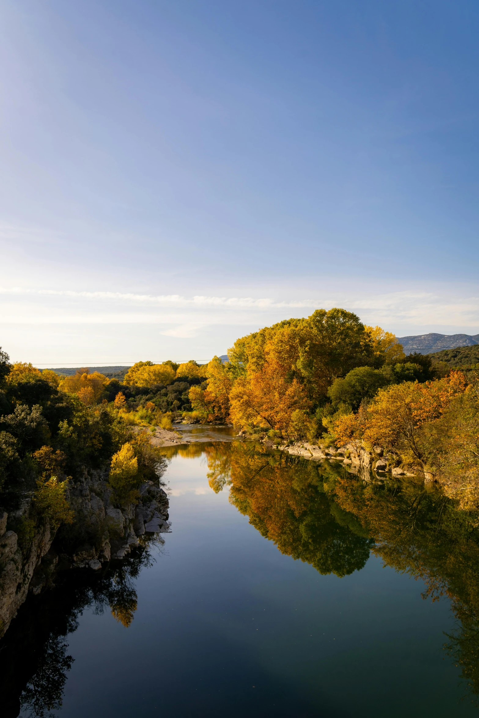 a river surrounded by green bushes and yellow trees