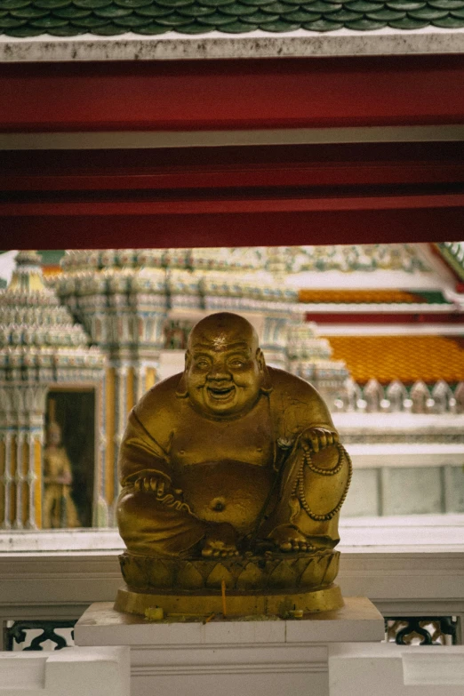 a gold statue under a red covered roof