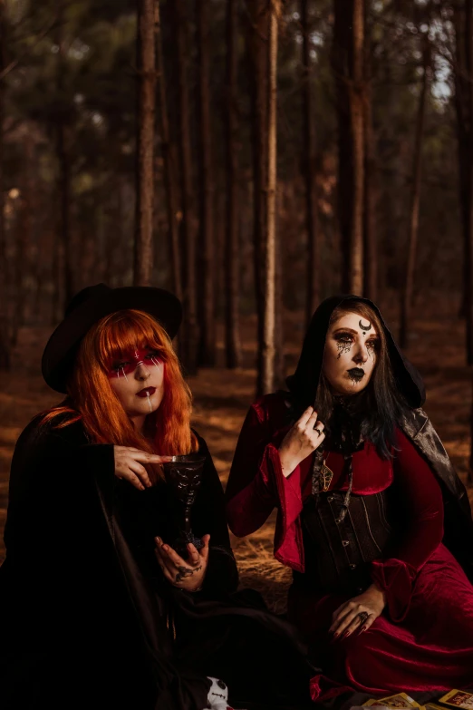 two girls sitting in the woods, one holding soing up