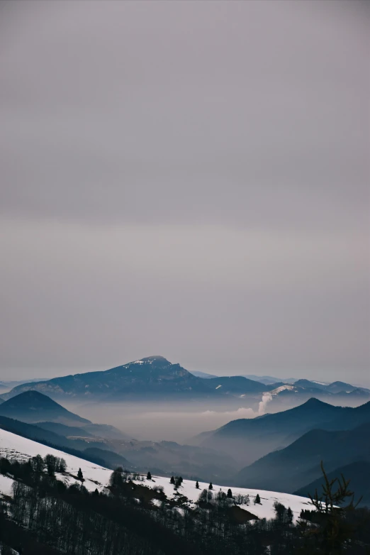 a mountain scene with fog and mountains on the horizon