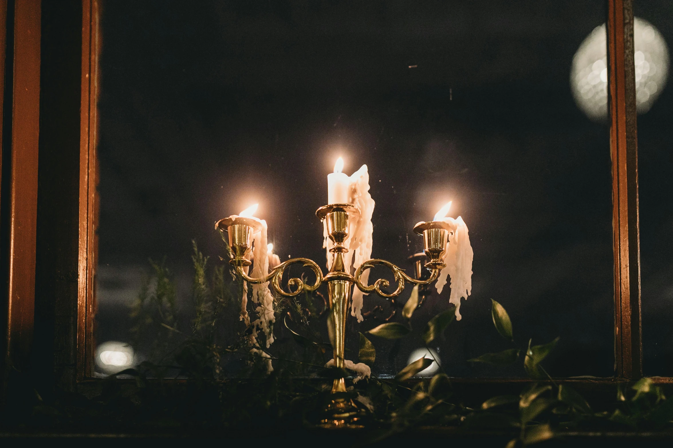 four lit candles sitting in a chandelier next to a mirror