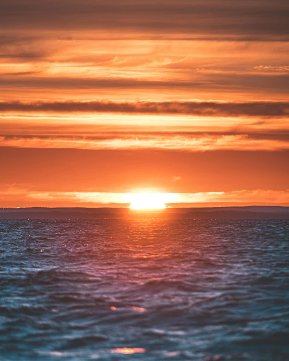 a bright orange sunset above a very cloudy ocean