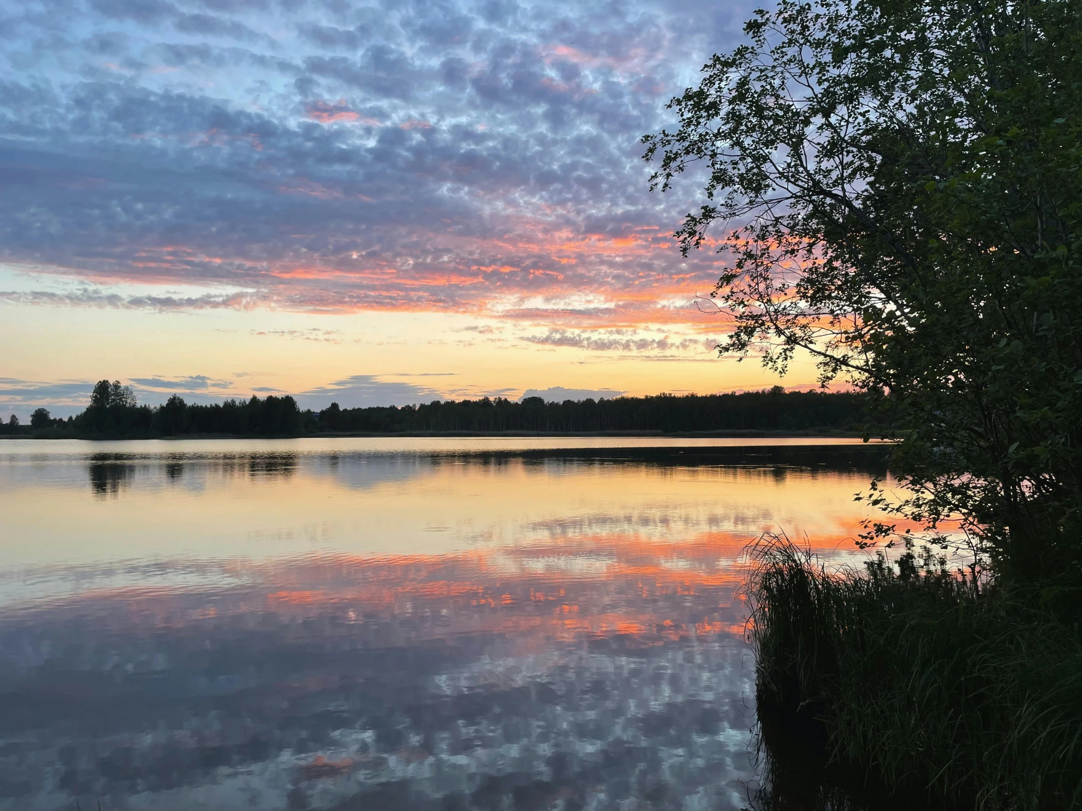 a sunset is reflected in the calm water