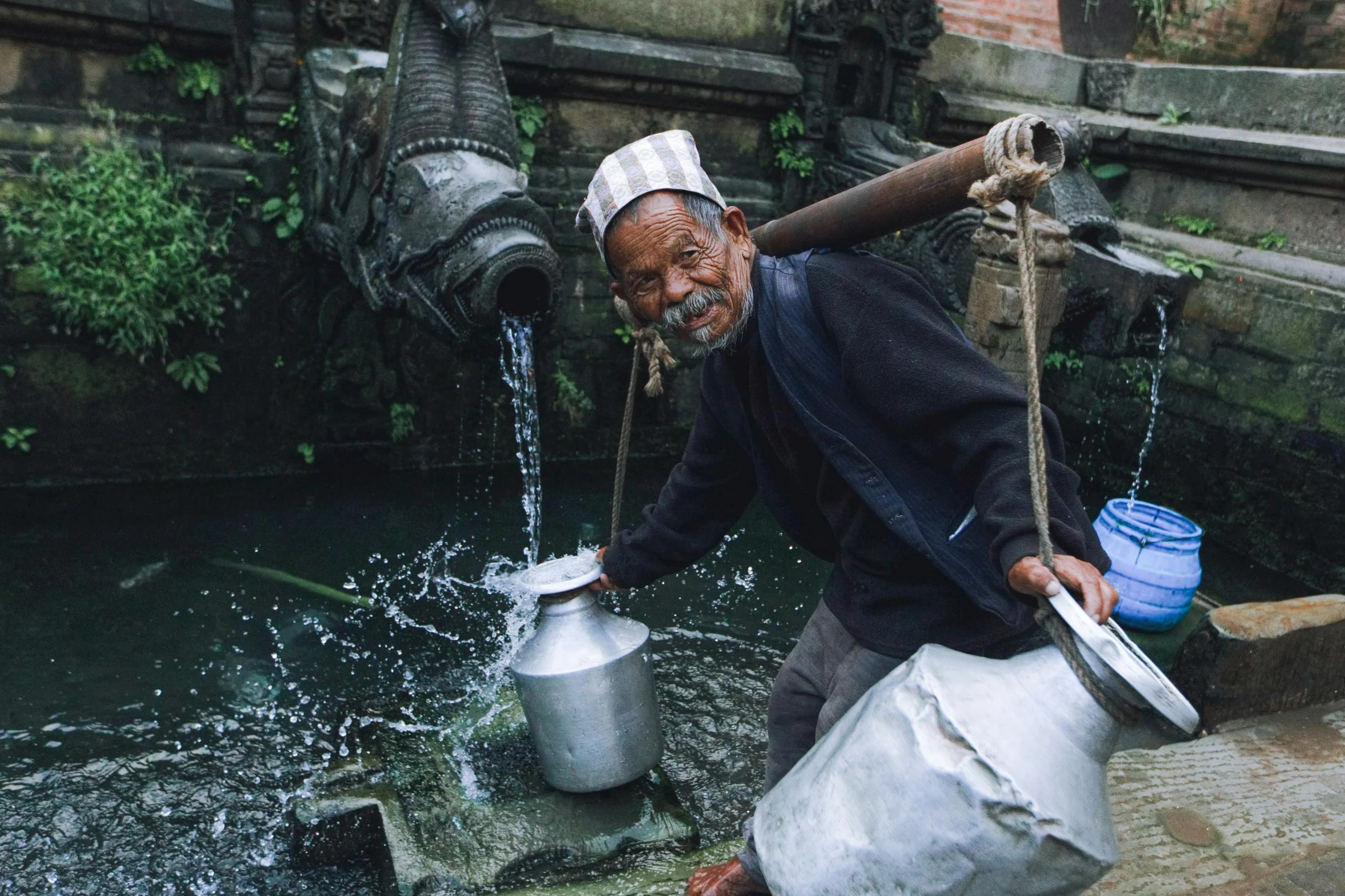 an old man holding two buckets full of water