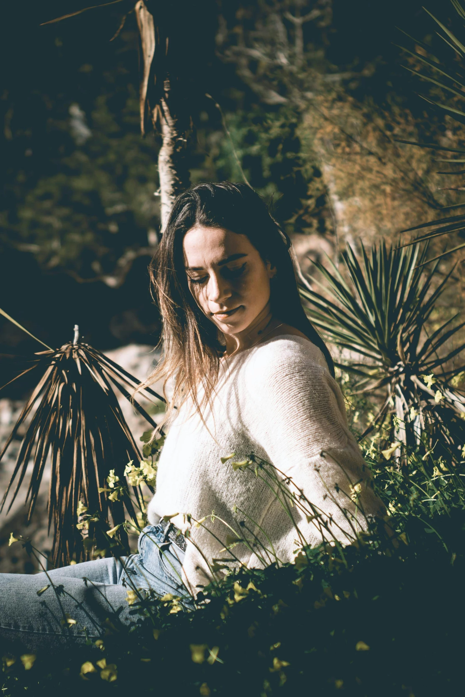 a woman sitting down with a plant behind her