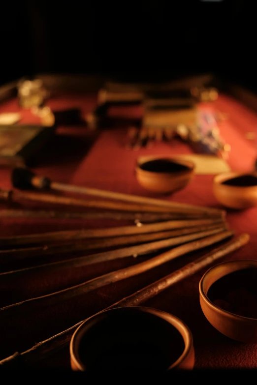 an array of asian chopsticks, bowls and utensils are laying on a red rug