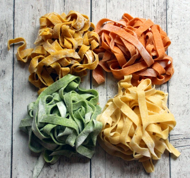 four different colored pasta types are shown on the floor