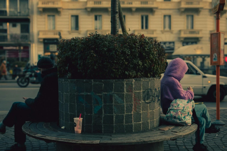 a teddy bear with a purple coat sitting on top of a wooden bench