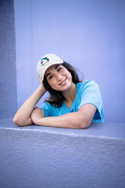 a girl smiles as she leans against the wall