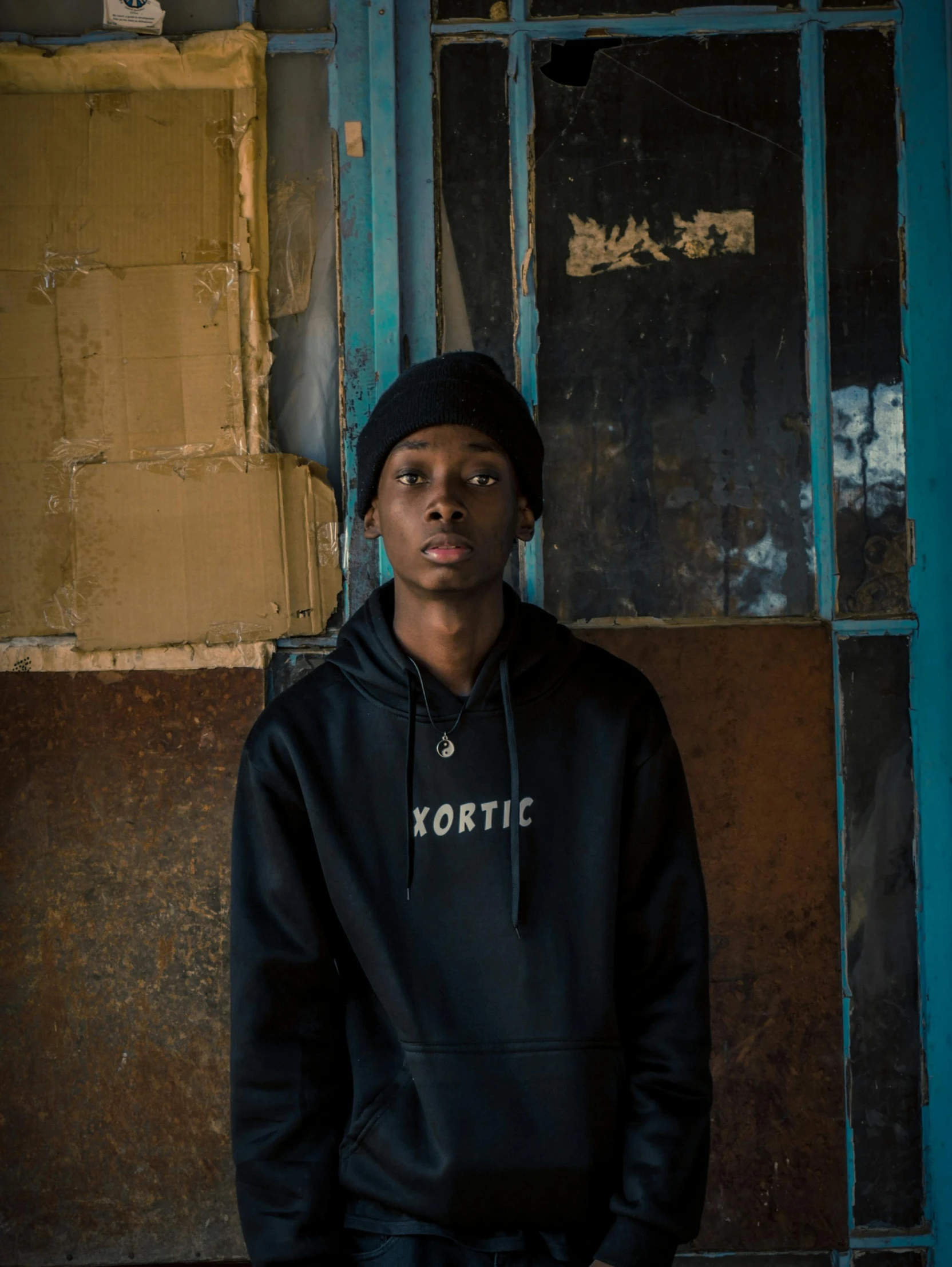 a young man in a black hoodie and pants standing by a door