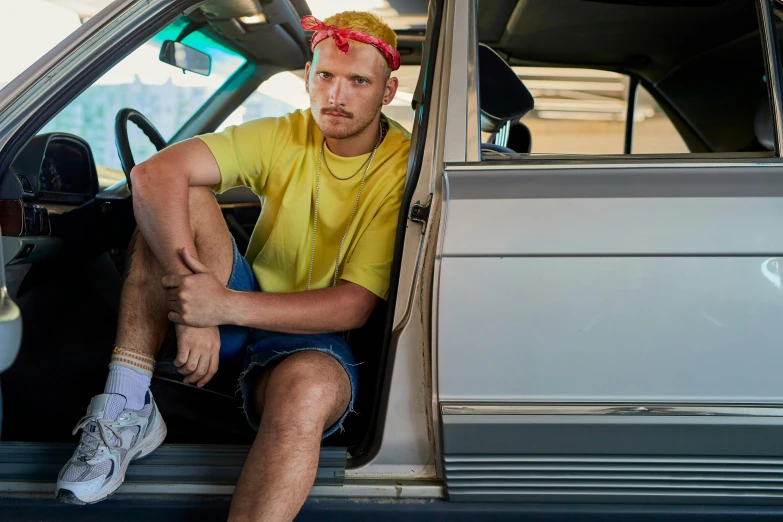 a man with red hair sitting in the driver's seat of a car