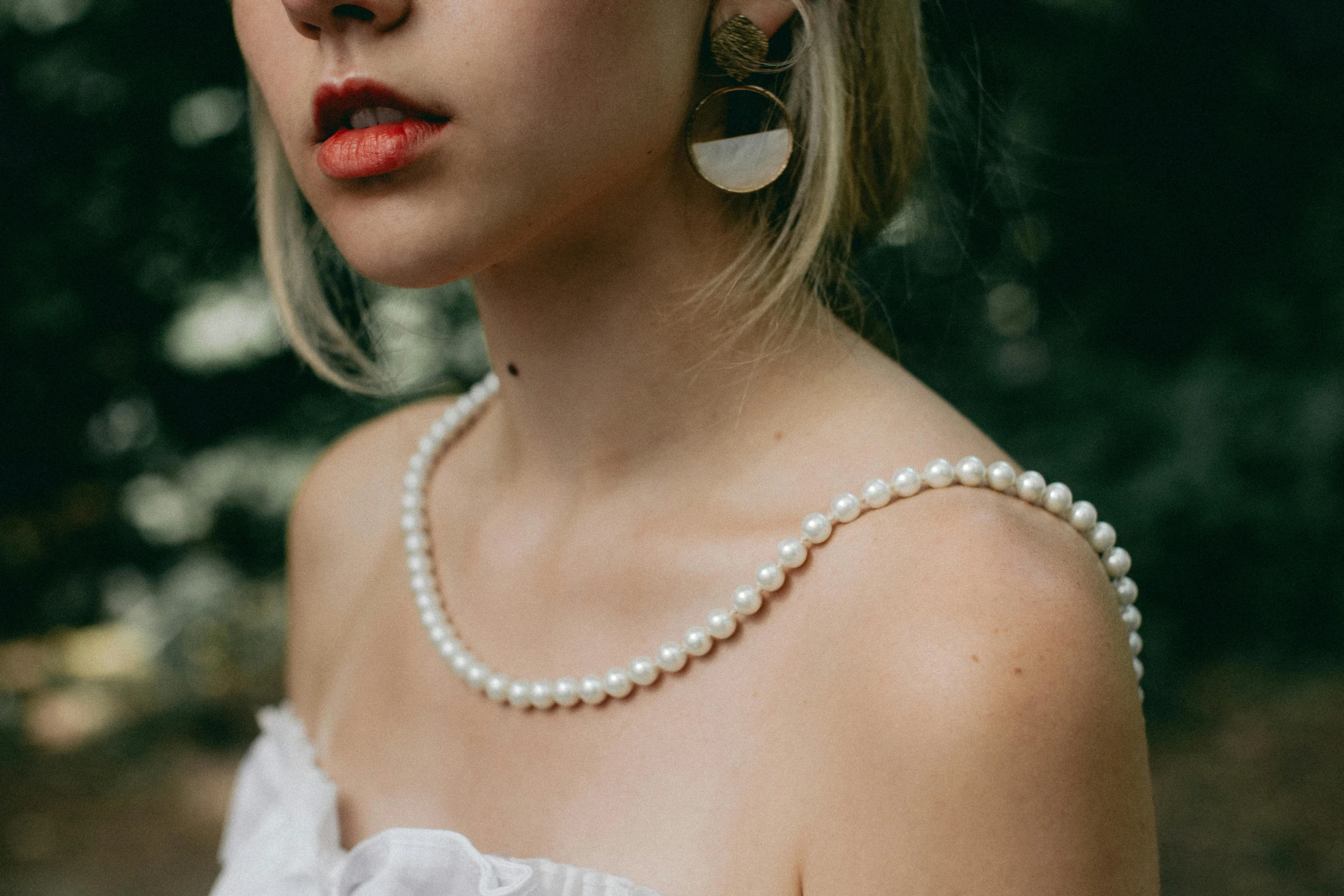 a beautiful woman wearing large earrings and a white top