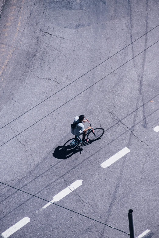 an aerial view of the cyclist riding down a street