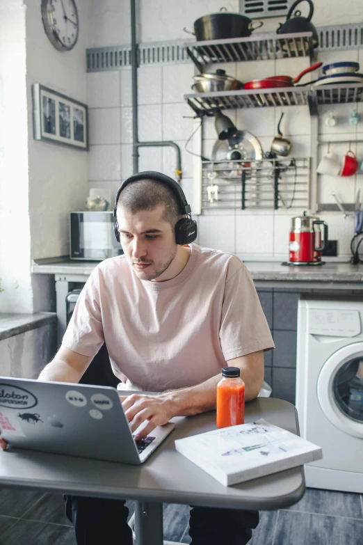 a man sitting in front of a laptop computer while wearing headphones