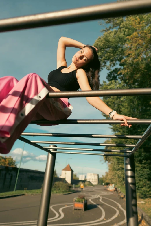 a young woman poses on a railing with her arm outstretched