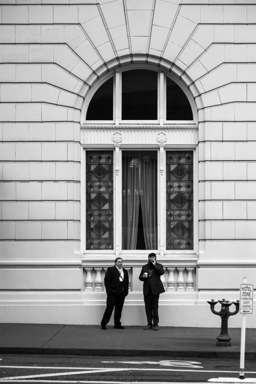 two men in uniforms posing next to an old building