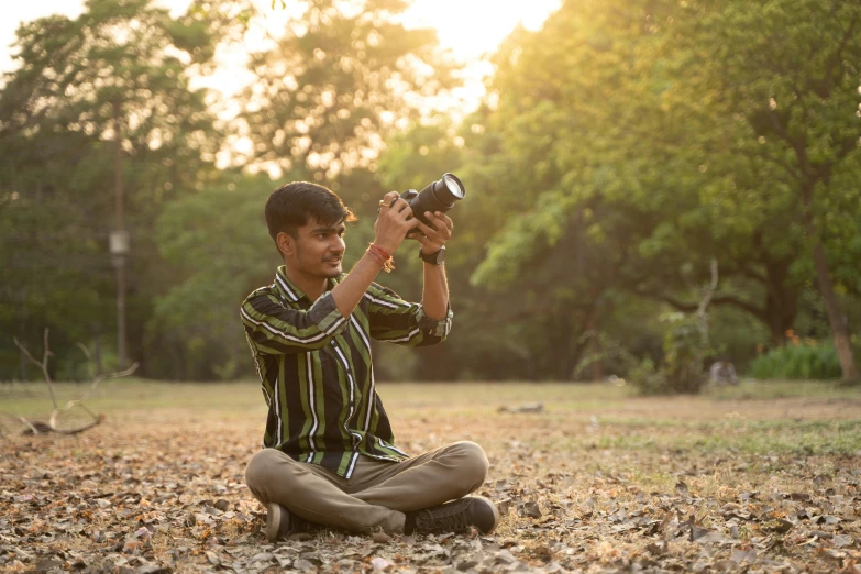 a boy sitting in the leaves holding a camera