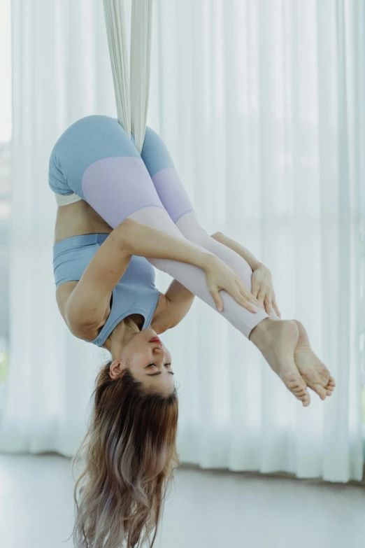 woman doing aerial acrobatic exercises near windows