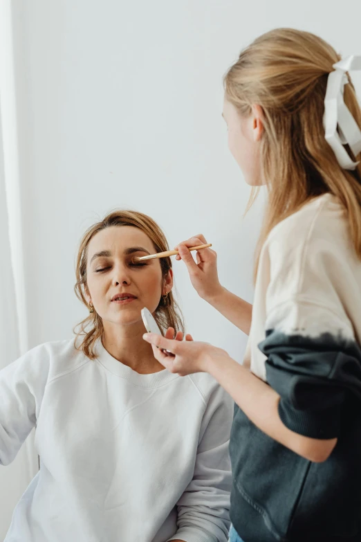 a  with a ponytail in her hair, putting on makeup