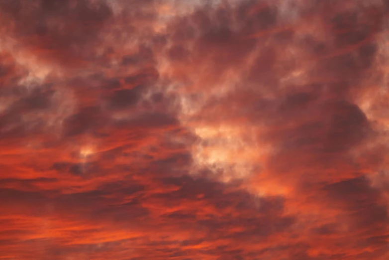 an airplane is flying through the red cloudy sky