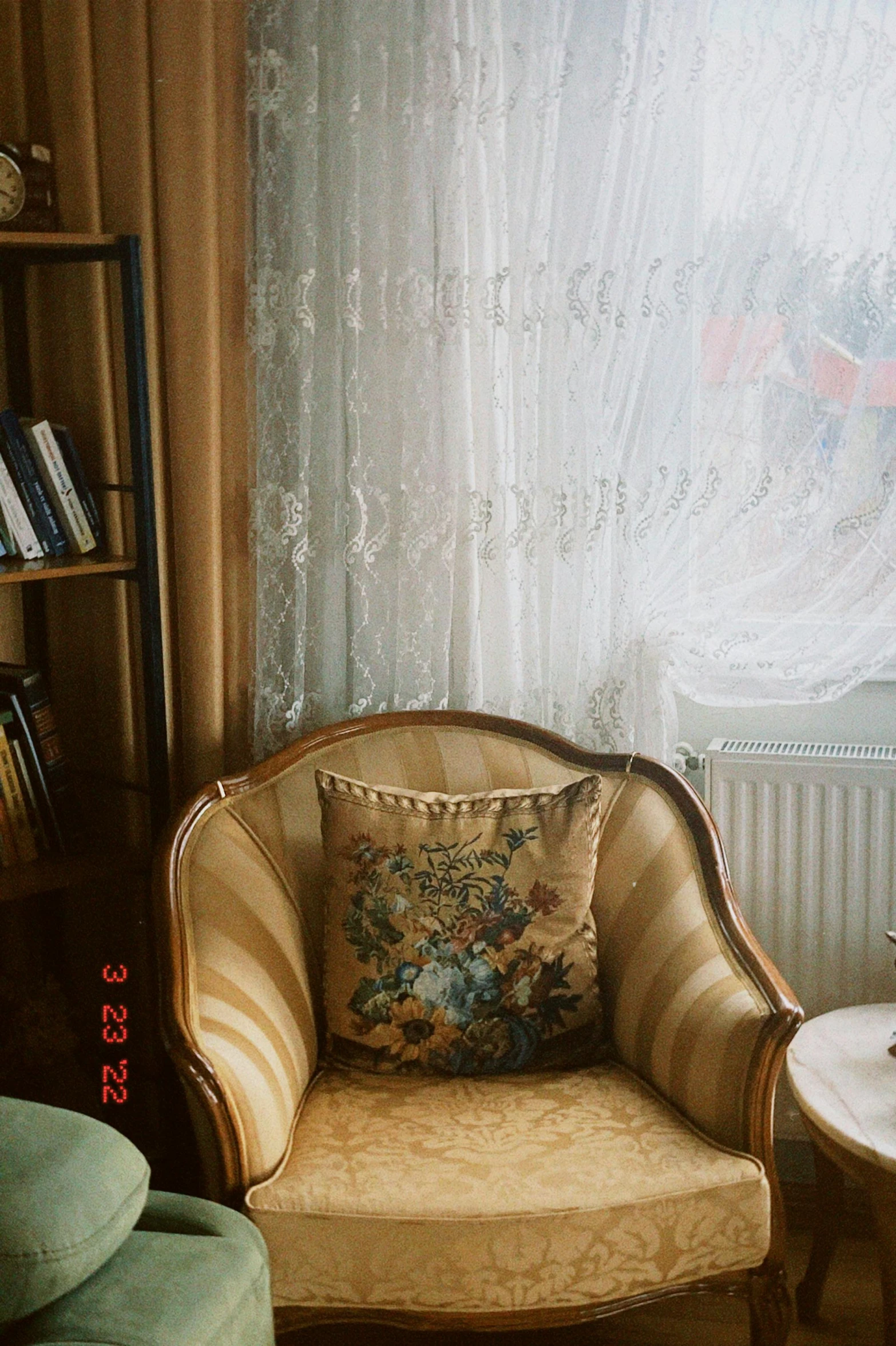 a brown chair sitting next to a book shelf and window