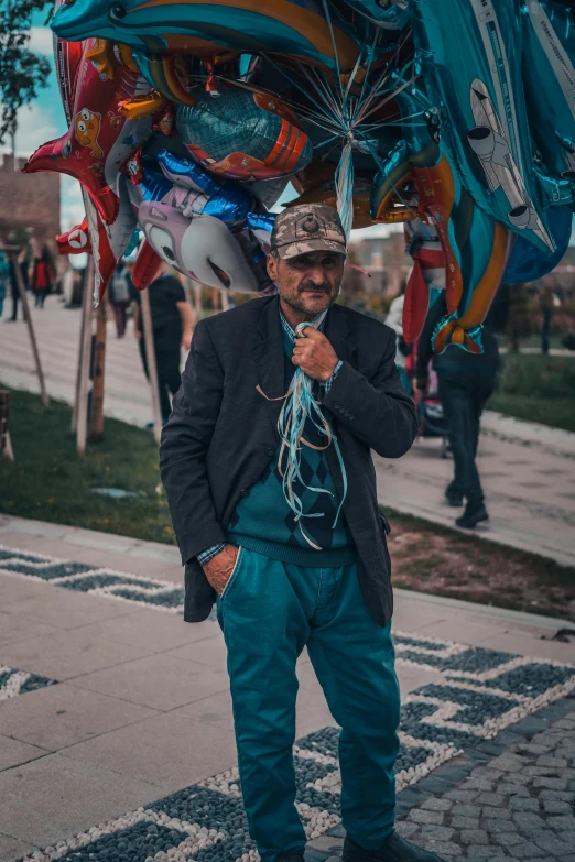 man standing underneath a large bunch of balloons