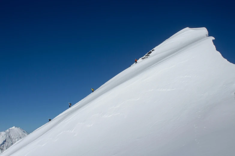 three skiers are riding down a steep slope