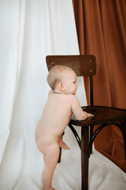 a  baby standing next to a chair