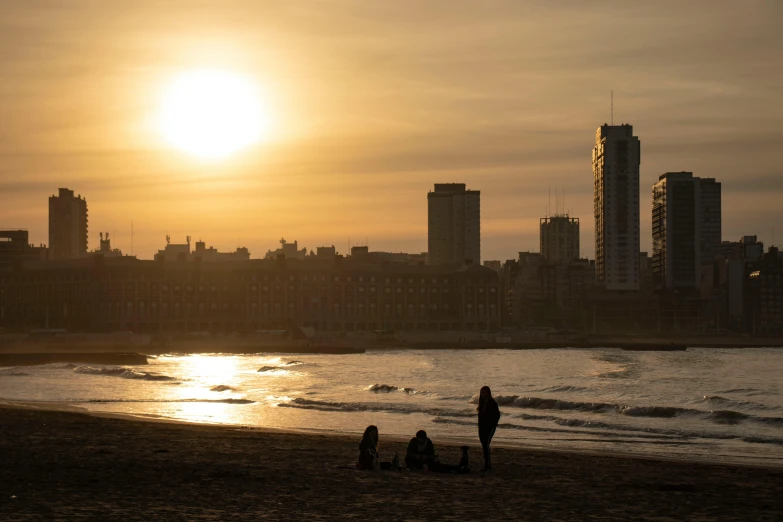 several people are on a beach and buildings in the background