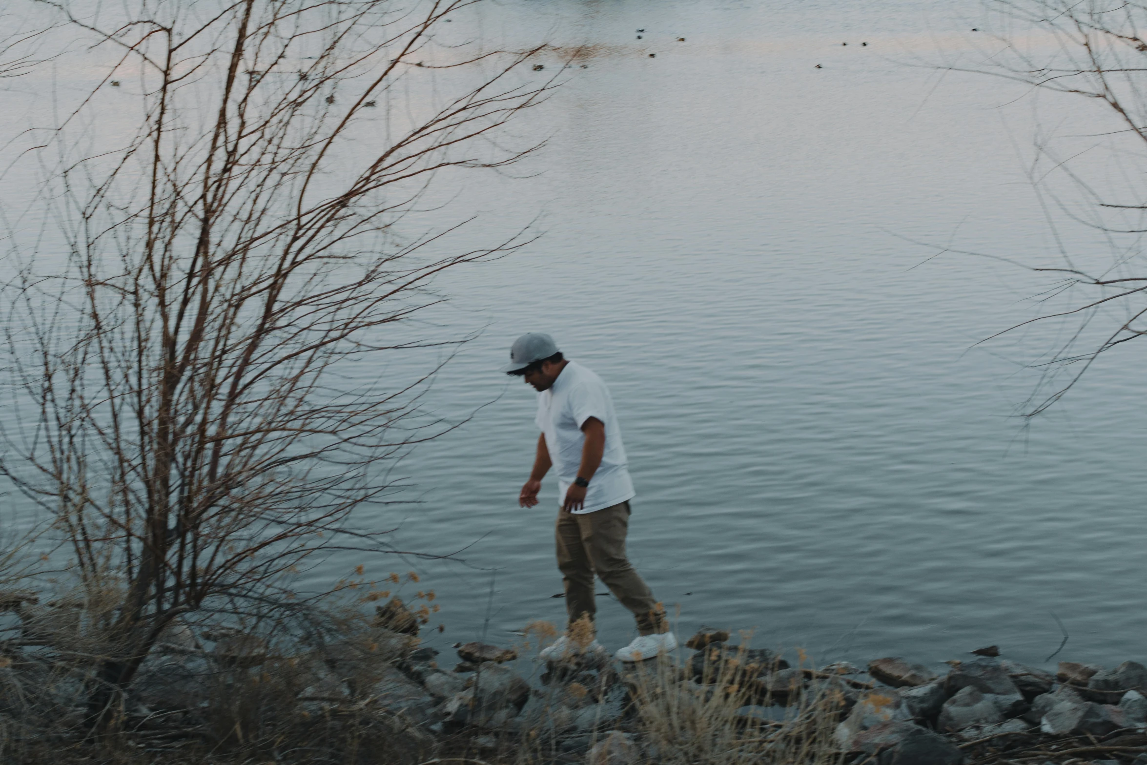 a man standing next to a body of water near trees