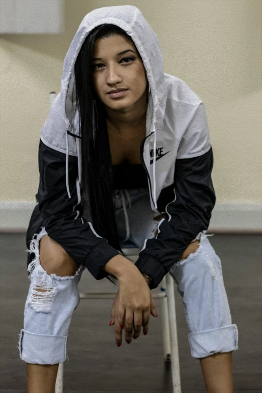 a woman sitting on a chair with ripped jeans