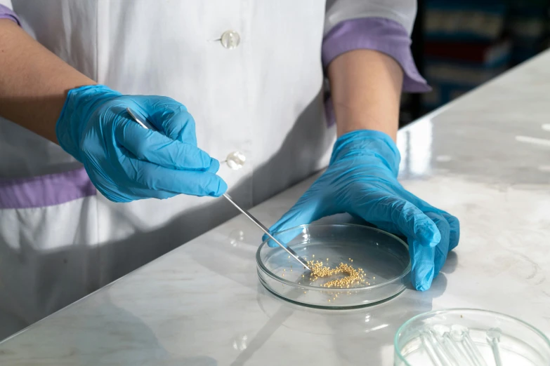 a person in blue gloves stirring up a glass bowl