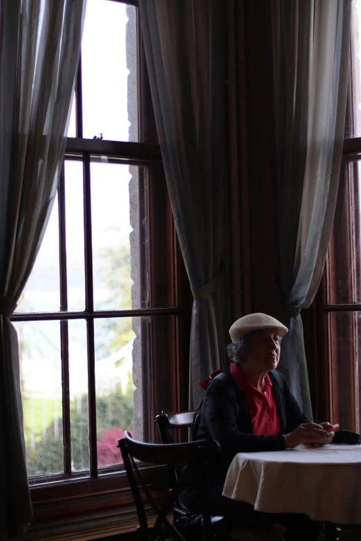 an old woman sitting at a table by the window