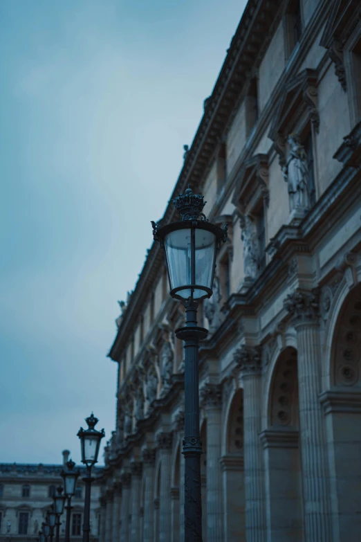 the tall light fixture on the street post has the old fashion style architecture and stone work