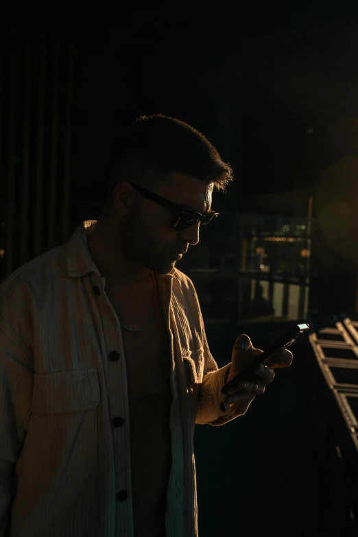 a man in a white shirt texting on his cell phone