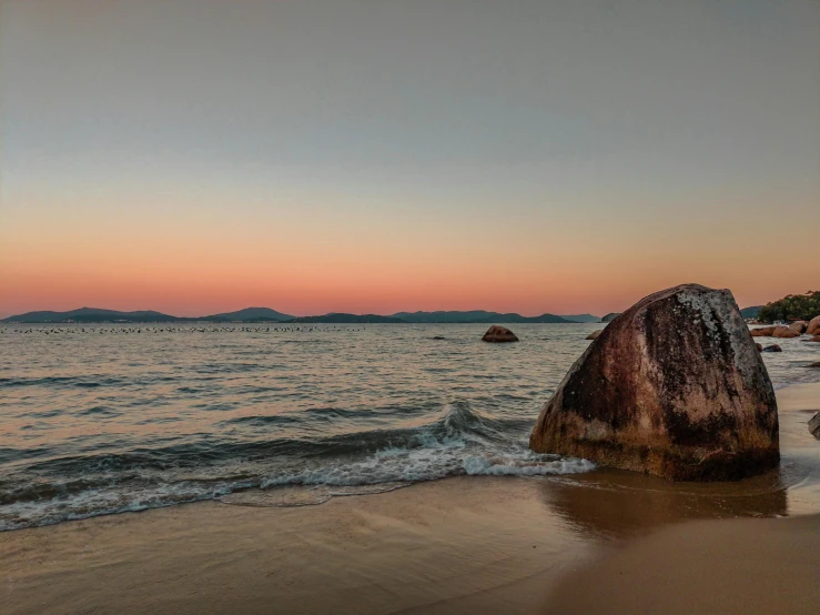 a large rock sticking out of the beach