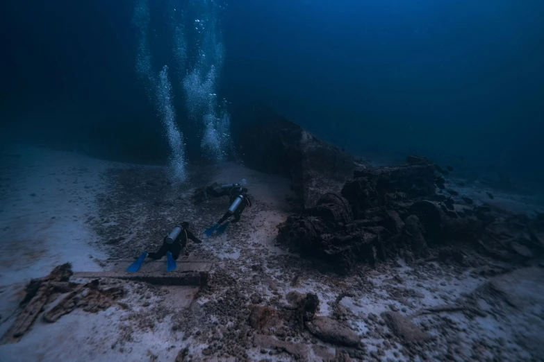 divers are looking at the remains of a ship underwater