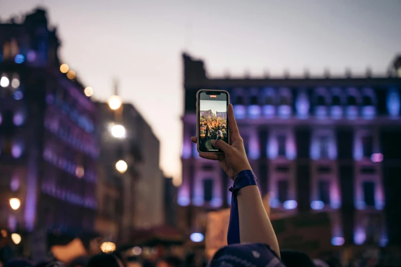 a person holding up their cell phone with the city in the background