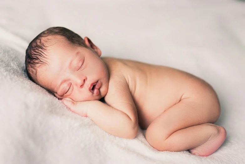 a small baby is sleeping on a white blanket