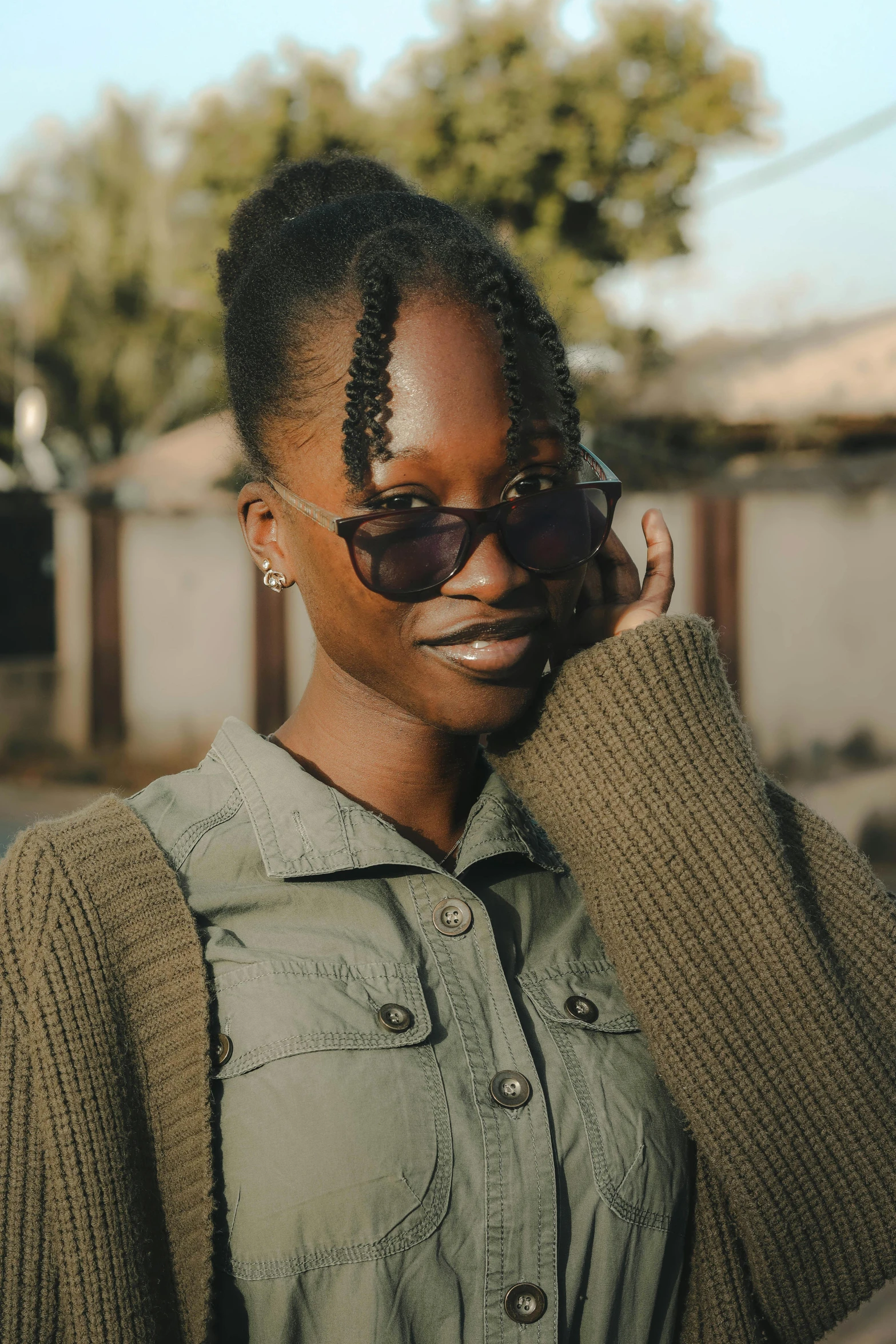 a woman wearing a green shirt and sunglasses on her cell phone