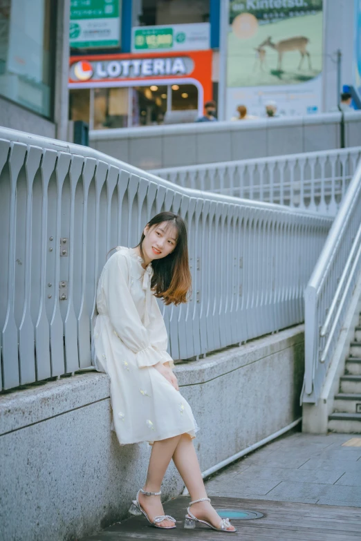 woman in white dress sitting against the wall