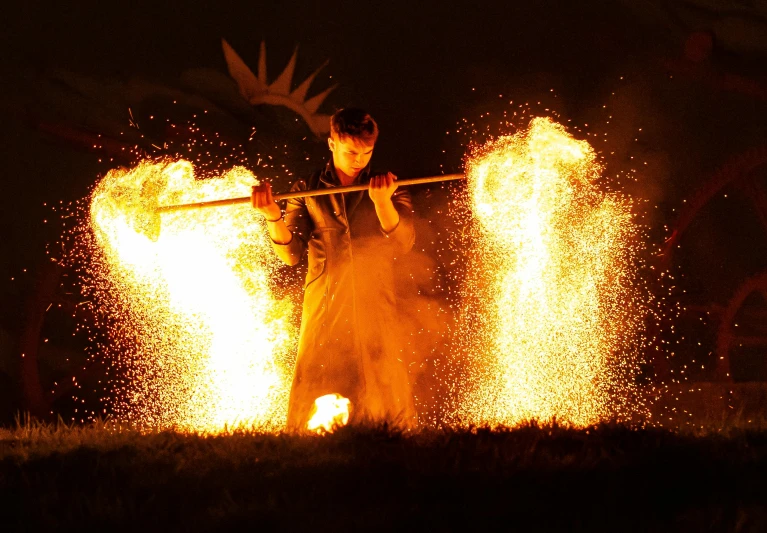 a person standing near a fire with their arms crossed