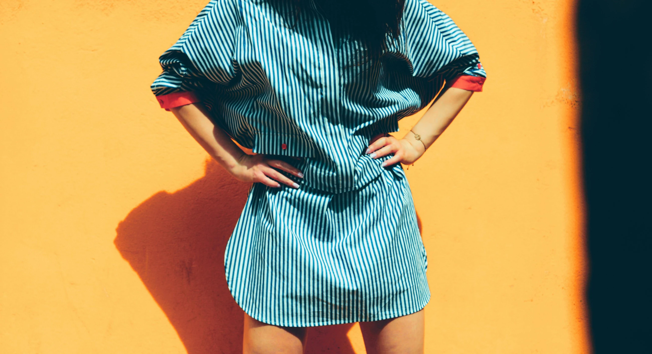 a person wearing a dress and boots near an orange wall