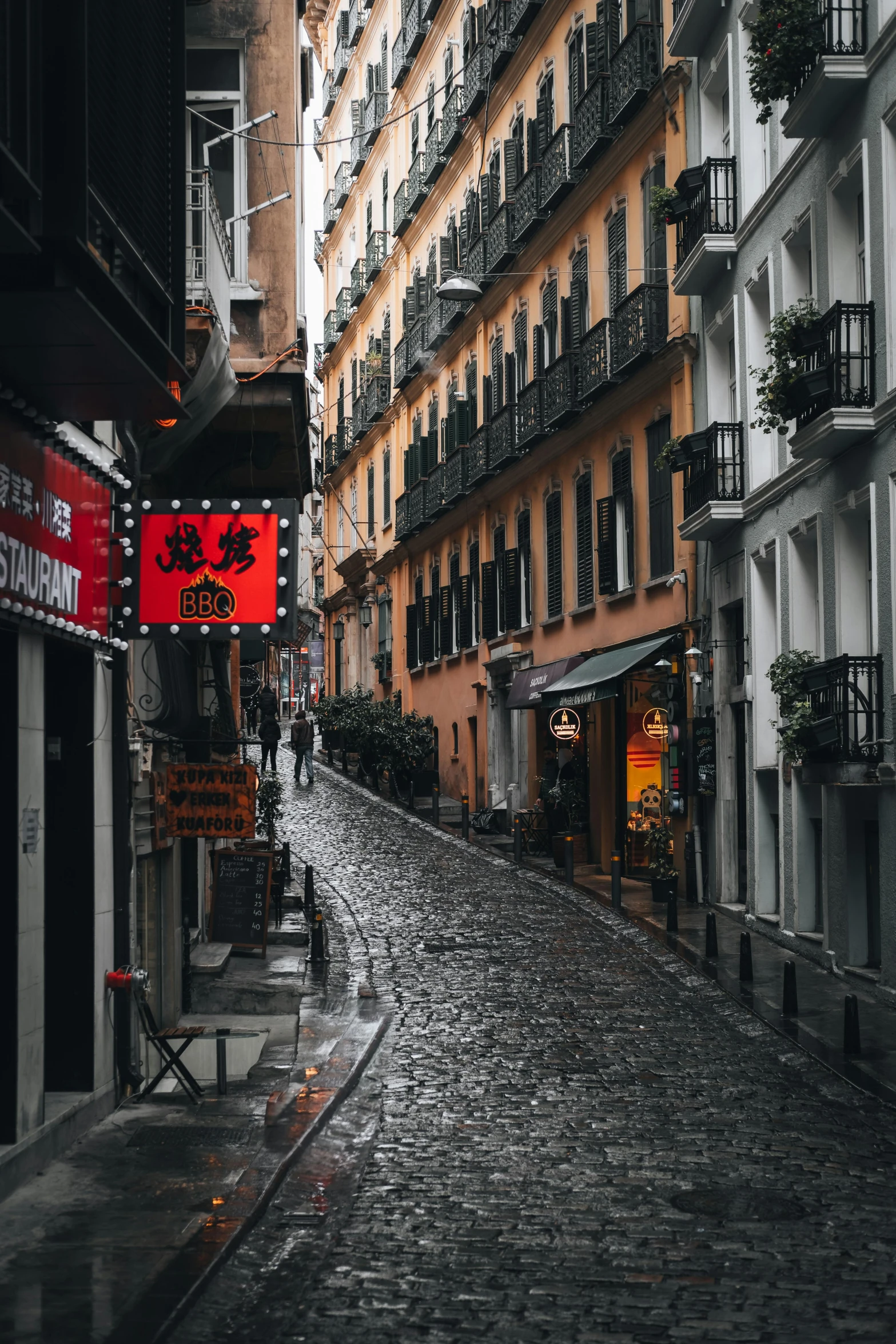 a wet street with buildings and people on it