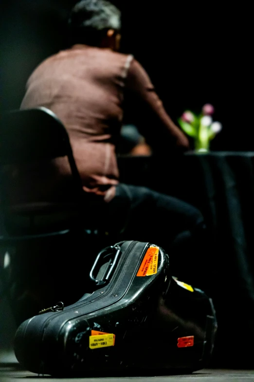 a close up of a suitcase and person on chair in background