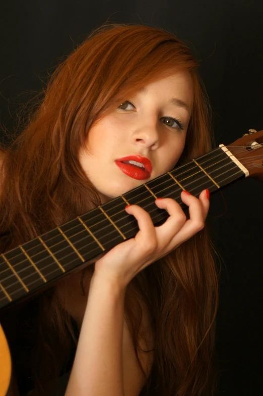 woman holding onto a guitar with a red lipstick