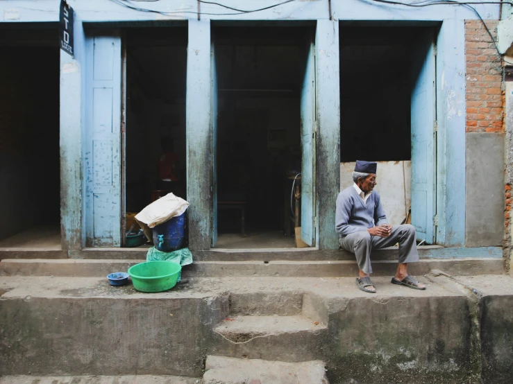 a man is sitting on stairs outside a door with a basket