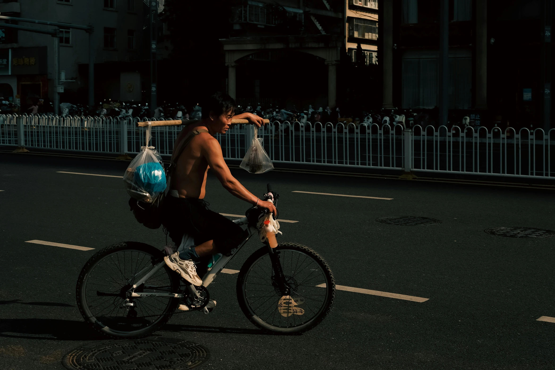 shirtless boy is riding a bike down the street