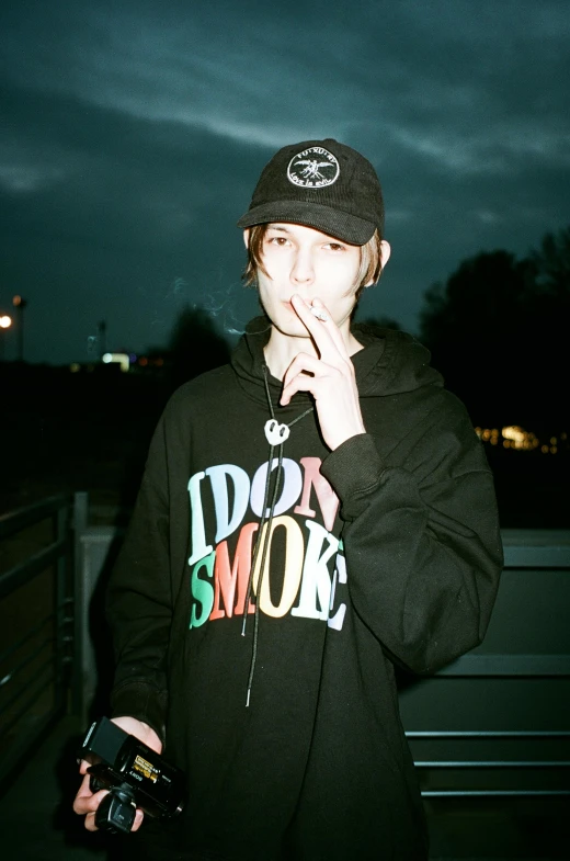 a man smoking a cigarette with an identum shirt