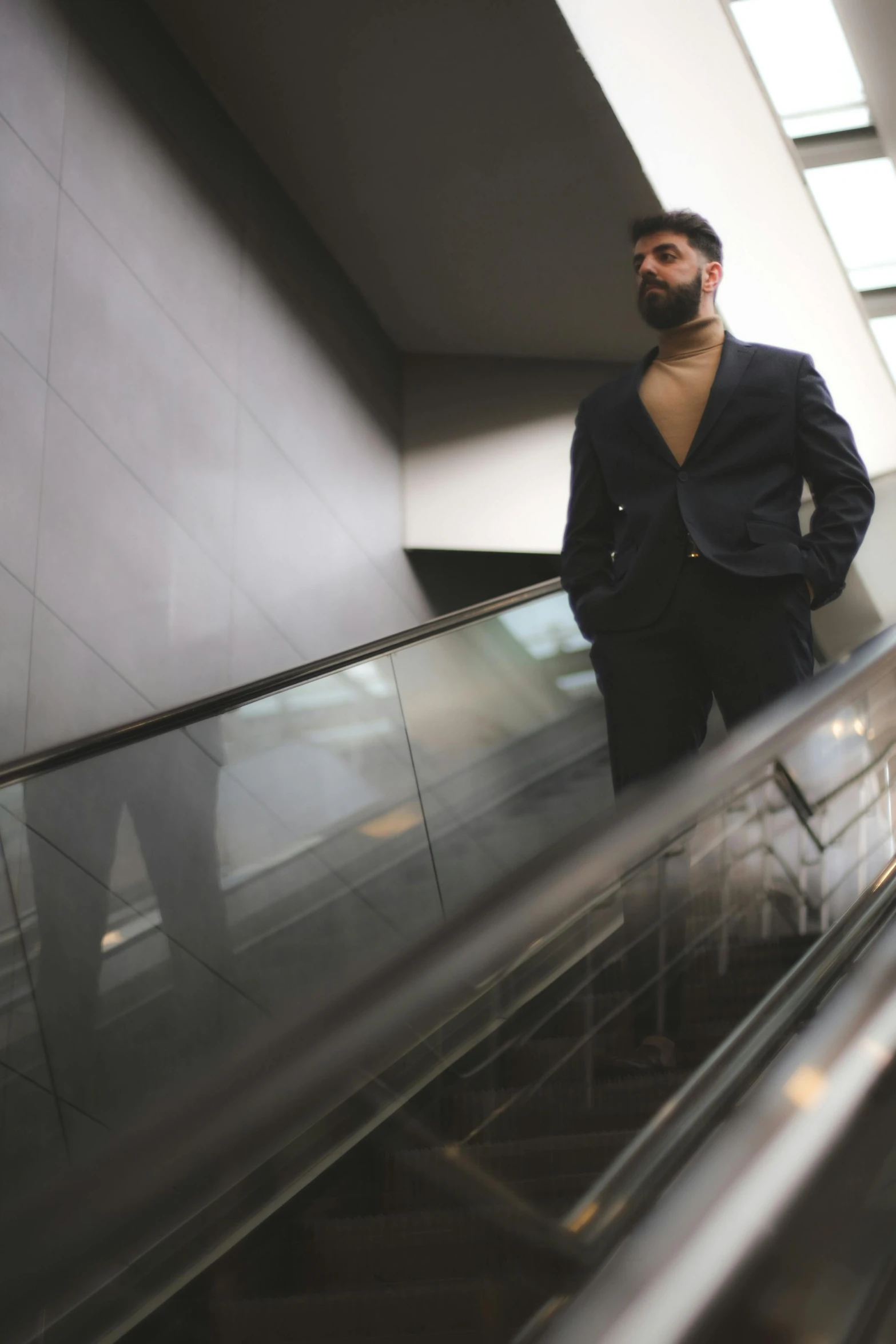 the man is standing on an escalator in a suit